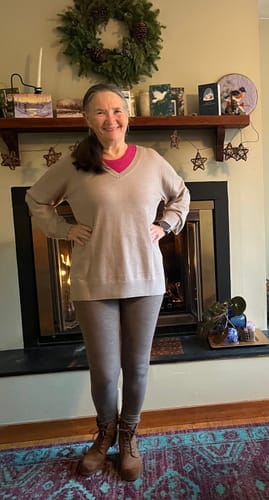 Reviewer standing in a living room, modeling a tan sweater from their Mystery Bag.