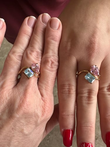 Two customers showing their matching Navae Birthstone Rings with bright pink and blue stones.