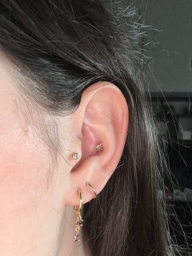 Customer wearing the gold Adelaine Huggies with dangling espresso-colored crystals in their ear.