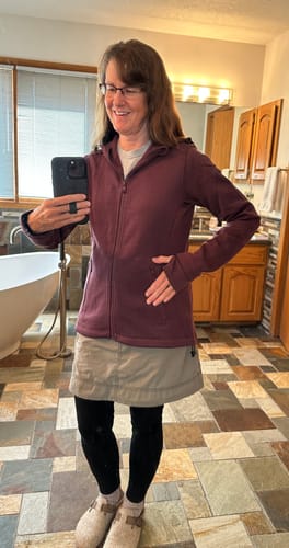 Reviewer in a bathroom mirror selfie wearing the grape harvest Cubby Hooded Sweatshirt, showing its fit and thumbholes.