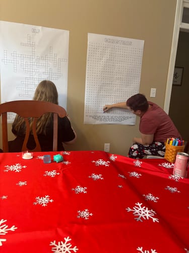 Reviewer's family working on the large Elf Giant Crossword Puzzle hanging on a wall during a festive get-together.