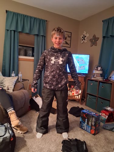 Reviewer shows a young person wearing the black Freedom Insulated Pants indoors.