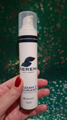 Egy vásárló a kezében tartja a SERENI Pikkelysömör és Ekcéma Krém fehér, pumpás flakonját.