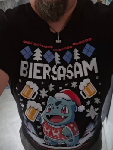 Ein Kunde trägt das schwarze BIERSASAM Weihnachtsshirt mit einem lustigen Cartoon-Motiv mit Weihnachtsmütze.
