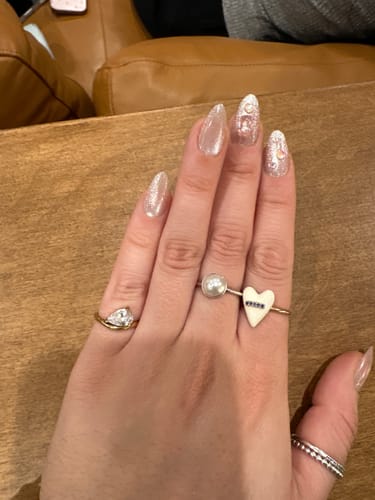 Reviewer's hand wearing the Pia Birthstone Ring with a pear-cut stone on their pinky finger, styled with other rings.