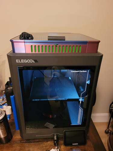 Customer's ELEGOO Centauri Carbon 3D printer on a wooden table with a custom, colorful top cover.