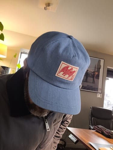 Reviewer wearing the light-blue unstructured denim hat, looking down.