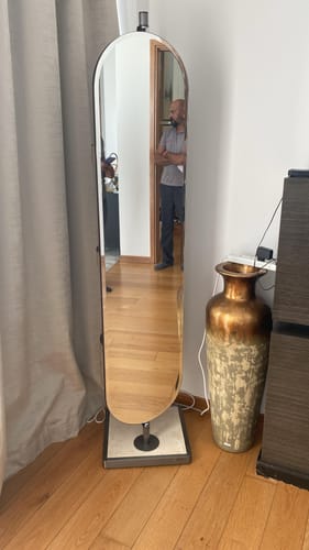 Reviewer's tall Saddle Leather Shelf/Mirror with a dark frame and a marble base, standing in the corner of a room.