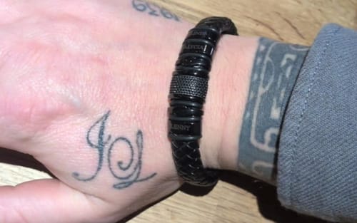 Customer wearing the personalized black bracelet on their tattooed wrist.
