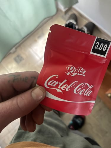 Customer holding the red 3.0G pouch of Cartel Cola THCA Flower.