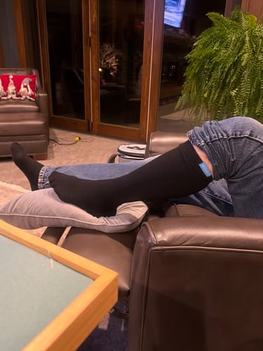 Customer resting after a knee replacement, wearing black Performance Eucalyptus Compression Socks.