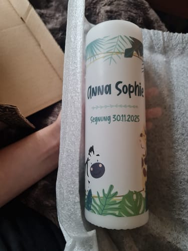 Rezensent hält die personalisierte 'Dschungel'-Kerze mit dem Namen 'Anna Sophie' und Tiermotiven in der Verpackung.