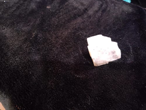 Reviewer's blue calcite crystal from the monthly club resting on a black surface.