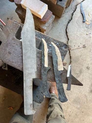 Customer's knife blades on an anvil, showing various stages of finish after using the sanding belts.