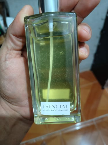 Primer plano del cliente sosteniendo el frasco de vidrio del perfume Esencial H215 Tobacco Vanille.