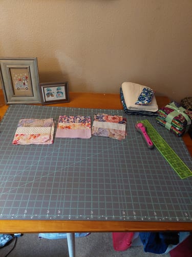 Customer's large Creative Grids Cutting Mat on a table with fabric squares and quilting tools.