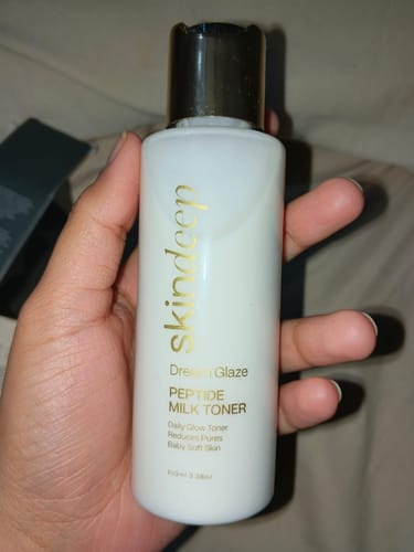 Reviewer holding the white bottle of Dream Glaze Peptide Milk Toner.