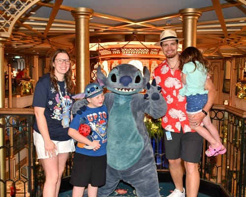 Customer wearing the red "He Mele No Lilo" shirt while posing with family and a costumed character.