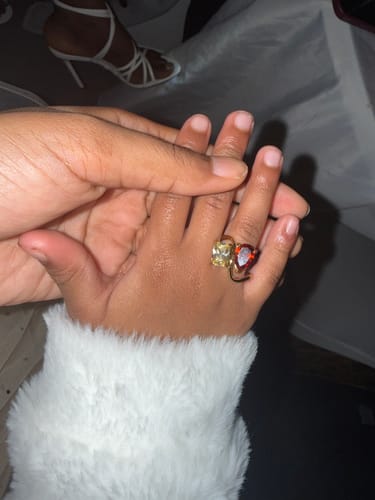 Customer's Navae Birthstone Ring with red and yellow stones worn on a child's hand.