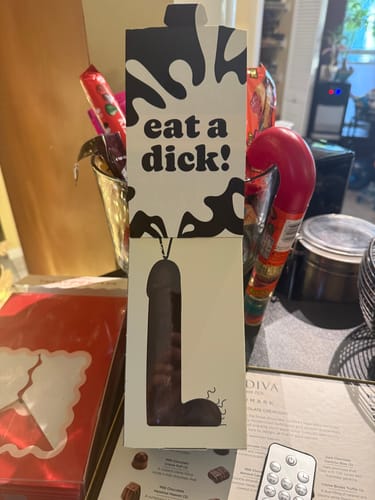 Reviewer's 'Eat a D' chocolate in its novelty box, which has text that reads 'eat a dick!'