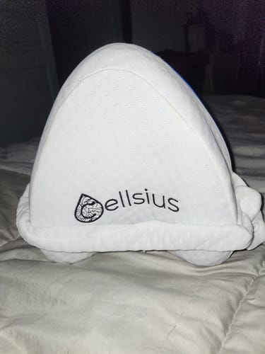 Un client montre son coussin orthopédique blanc Cellsius posé sur un lit.