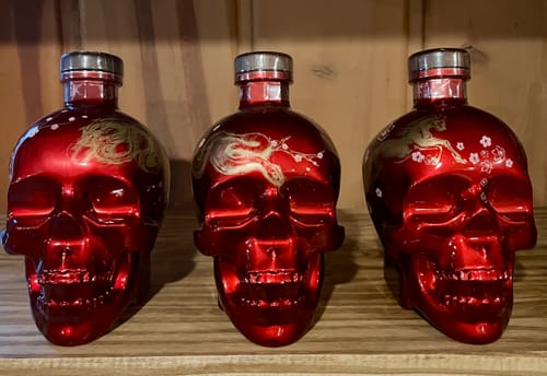 Reviewer's three red Crystal Head Vodka Year of the Horse bottles displayed on a wooden shelf.