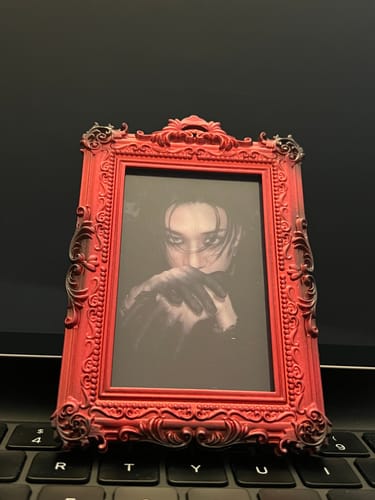 Customer's red ornate WORK OF ART FRAME PHOTOCARD HOLDER holding a photocard while standing on a laptop keyboard.