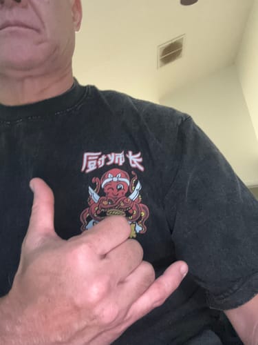 Close-up of a customer wearing the black Chef Octopus Vintage T-Shirt and making a shaka hand sign.