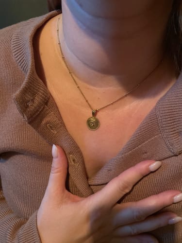 Reviewer wearing the delicate, gold St. Christopher Necklace with a beaded chain.
