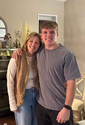 Customer wearing the buttercream Hannah Long Sleeve Top layered under a brown vest while smiling indoors.