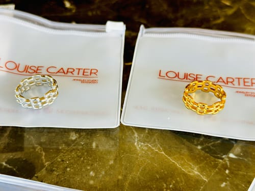 Customer displays two woven-style rings from their bundle, one in a gold tone and the other in silver.