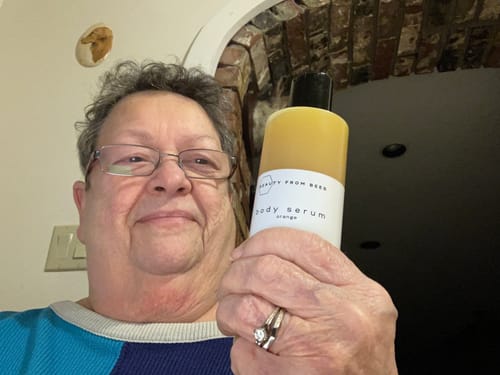 Customer holding a bottle of the orange-scented Body Serum.