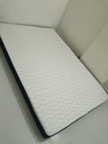 Customer's white Flo Mattress Ortho with a wavy pattern and dark sides, placed on the floor.