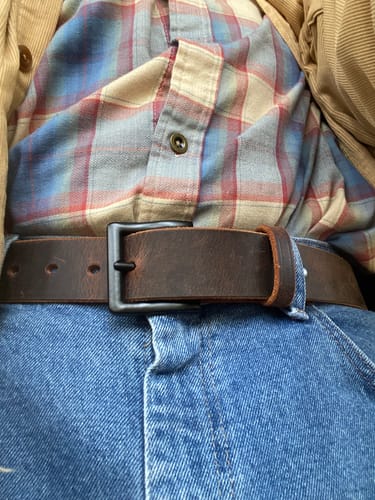 Close-up of a customer wearing the rich brown Crazy Horse belt with blue jeans and a plaid shirt.
