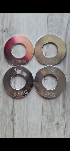Customer's four shiny Powerlifting Steel Plates, showing two 0.25kg and two 0.5kg weights on a floor.