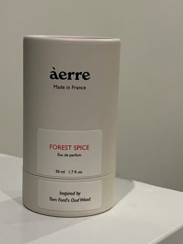 Customer's Forest Spice perfume in its off-white cylindrical tube packaging, sitting on a white shelf.