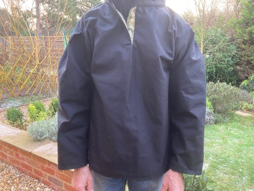 Customer wearing a black, shower-proof top made from the Water Resistant Waxed Cotton Fabric, with a colourful placket.