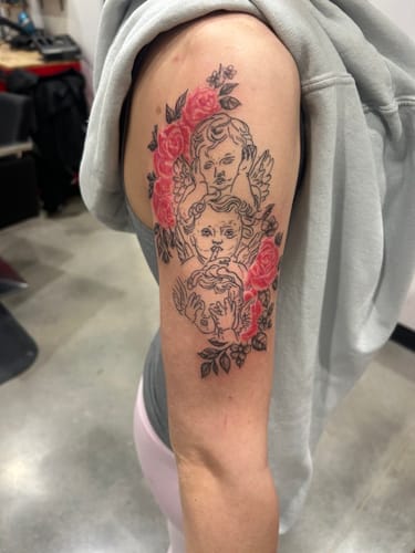 Customer shows their new arm tattoo of cherubs and roses after a session using Painless Tattoo Numbing Cream.