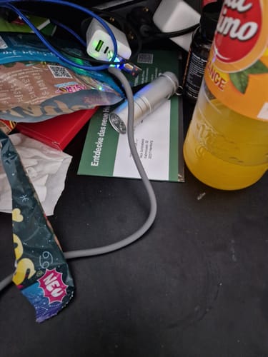 Rezensent zeigt das graue 4-in-1-Ladekabel, das auf einem Schreibtisch in ein weißes Netzteil eingesteckt ist und leuchtet.