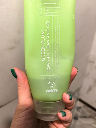 Клиент държи почистващия гел OOTD Green Plum Low PH в светлозелена туба.