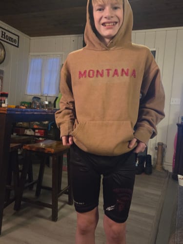 Customer's photo of a young person smiling while wearing the black 'Shield of Strength' Youth Performance Shorts.