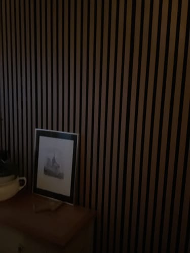 Customer's light oak Acoustic Slatted Wall Panels installed on a wall in a dimly lit room with a picture frame in front.