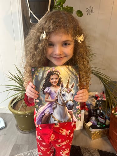 A customer's child holding her personalized Lavender Unicorn Princess artwork.