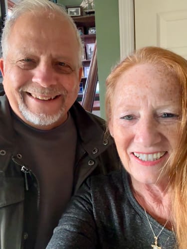 A happy reviewer with her husband, smiling and showing her glowing skin.