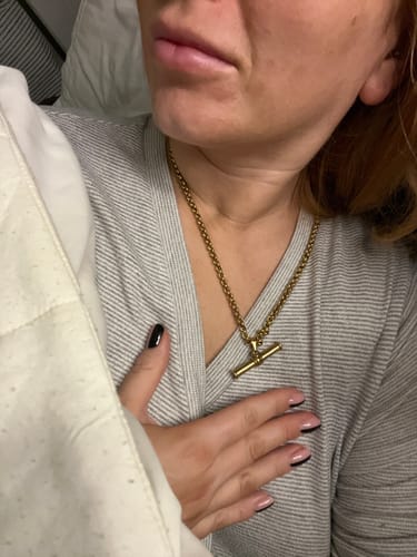 A customer wearing their gold XL T-Bar Necklace against a grey striped top.