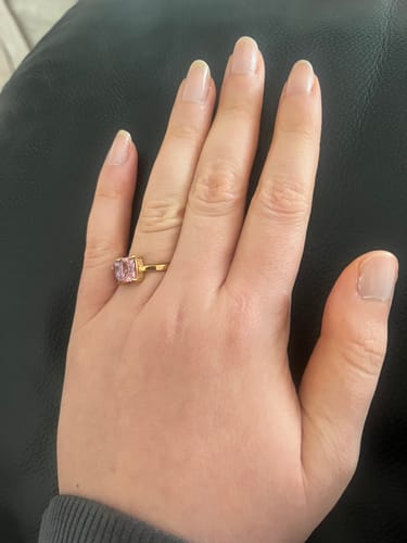 Customer's hand wearing the Toi Et Moi Birthstone Ring with pink stones and a gold band.