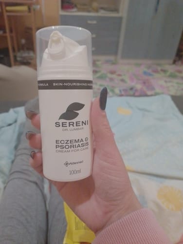 Vásárló kezében tartja a fehér flakonos SERENI Pikkelysömör és Ekcéma Krémet.