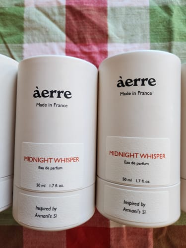 Customer's two white bottles of Midnight Whisper perfume standing side-by-side on a checkered surface.