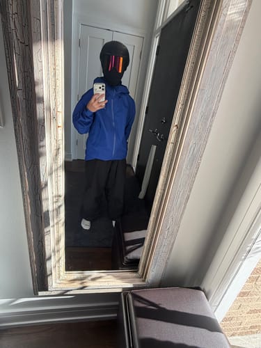 Reviewer taking a mirror selfie to show the fit of the baggy black snow pants.