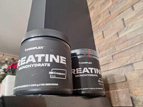 Reviewer's two black tubs of Complex Creapure Creatine placed on a shelf.